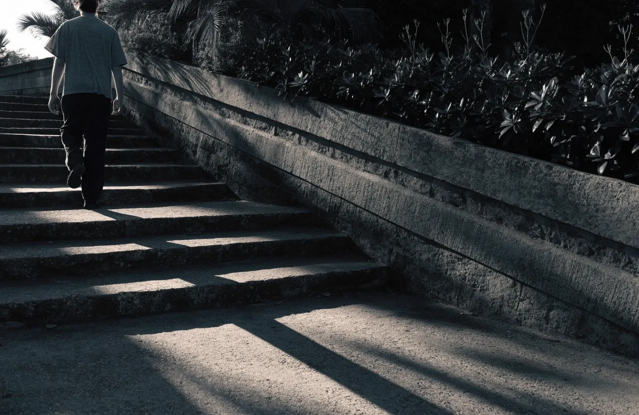 Man walking up concrete steps beside a tropical wall in early daylight